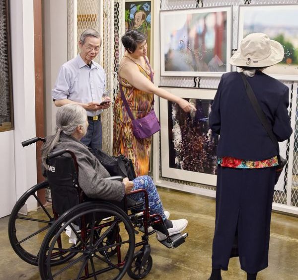 Four people in conversation about artworks hung on a rack.