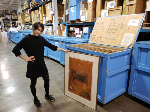 Photograph of Isabelle Chartier in the Art Bank warehouse with an artwork by Joyce Majiski 