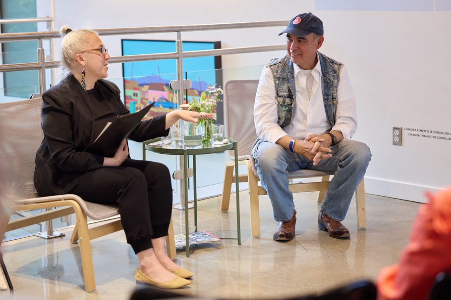 A woman and man are engaging in a conversation in front of a blurred audience