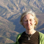 Photo of a woman looking at the camera and smiling with mountains in the background