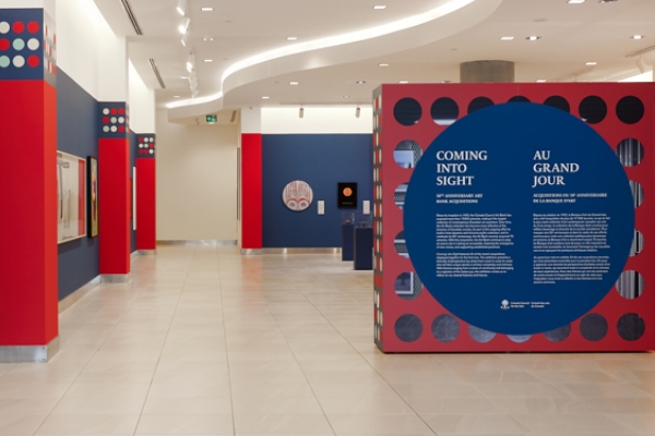 View of exhibition title wall, with artworks of various formats on the dark blue walls of the Âjagemô exhibition space.